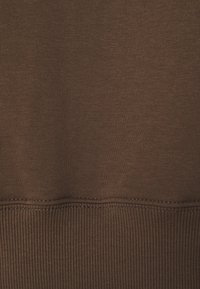 Tissu brun présentant une texture lisse avec un ourlet côtelé. Les coutures sont d'une teinte légèrement plus claire, mettant en valeur les coutures.