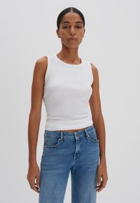 Top a maniche lunghe bianco a coste con scollatura tondeggiante, design aderente e lunghezza corta, abbinato a jeans di denim azzurro chiaro. Texture del tessuto liscia.