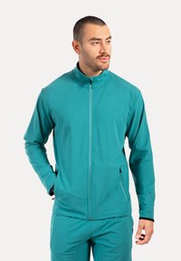 Türkisfarbene Zip-Jacke mit hohem Kragen, langen Ärmeln und Seitentaschen; aus glattem, dehnbarem Stoff für Komfort gefertigt.