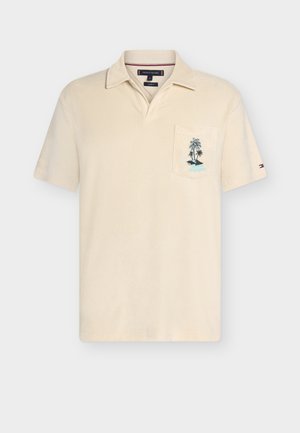 Beige polo t-shirt med korte ærmer og krave, brystlomme med palmebroderi og lille logo på venstre ærme.