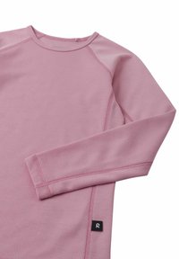 Różowy top z długim rękawem wykonany z teksturowanej tkaniny, z raglanowymi rękawami i kontrastowymi przeszyciami. Na dole znajduje się mała metka z logo.