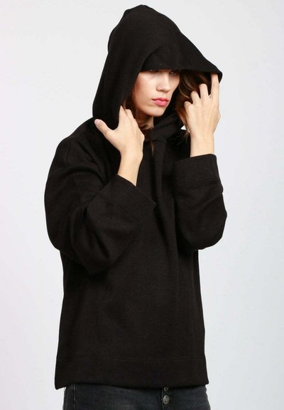 Felpa nera con cappuccio, vestibilità ampia, maniche larghe e tasca a marsupio. Il tessuto sembra morbido e strutturato.