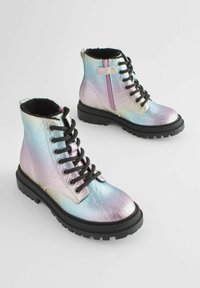 Bottines iridescentes avec une surface texturée, des lacets noirs, une fermeture éclair sur le côté et une semelle en caoutchouc pour la traction. Doublées de fourrure noire.