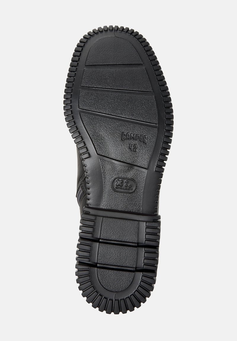 Black rubber shoe sole with a textured design; features ridged edges and an embossed logo. Flat and wide shape for stability.