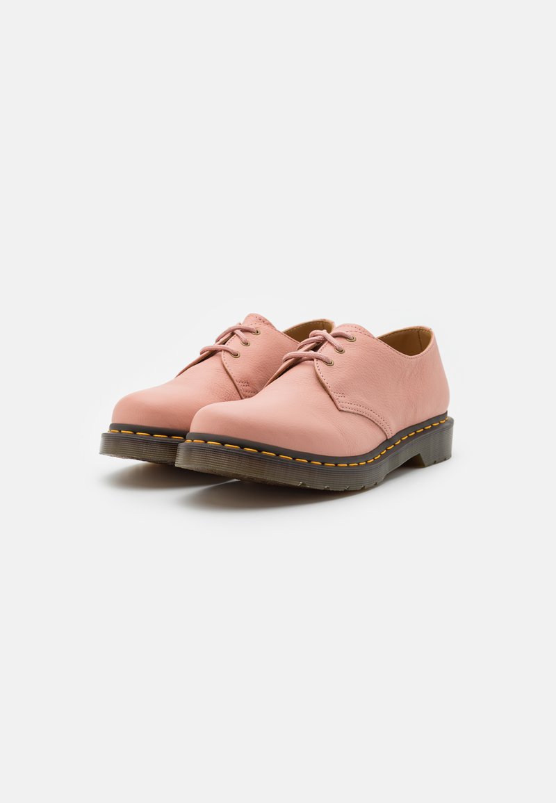 Chaussures en cuir rose à lacets avec un bout rond, des coutures jaunes contrastantes et une semelle épaisse noire. Texture lisse et design minimaliste.