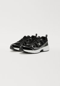 Black athletic shoes with mesh panels and glossy accents, featuring a white sole and laces, rounded toe, and prominent logo detail.