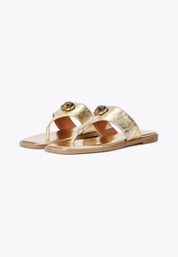 Sandali metallici dorati con suola piatta, caratterizzati da un design a ciabatta e decorazioni a forma di rosa sugli strap. Texture superficiale liscia.