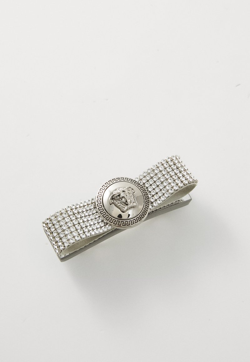 Silver hair clip with rhinestone embellishments, featuring a central round emblem design with intricate detailing and a smooth texture.