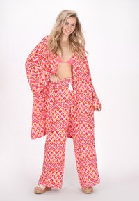 Bloemenpatroon strandcover-up in tinten van roze en oranje, met een losse pasvorm, wijde mouwen en franjes aan de taille.