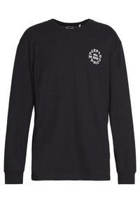Schwarzes Langarm-T-Shirt aus Baumwolle. Verfügt über ein kleines weißes Grafikmotiv im linken Brustbereich. Klassischer Rundhalsausschnitt und gerippte Bündchen.