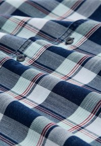 Karierte Hemd in Marineblau, Weiß und Grün; mit roten und weißen Streifen, sichtbaren Knöpfen und einem strukturierten Stoffmuster.