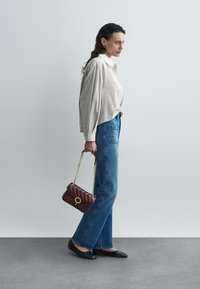 Καρό πουκάμισο με κουμπιά, μπλε τζιν, μαύρες μπαλαρίνες, και μια μπορντό κομψή τσάντα με επένδυση και χρυσές λεπτομέρειες.