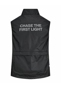 Zwarte mouwloze vest met een hoge kraag, met de tekst "CHASE THE FIRST LIGHT" in vet, reflecterend zilver op de achterkant.
