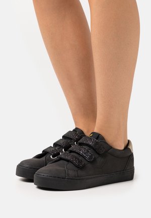 Black sneakers with glittery black Velcro straps, round toe, and textured material. Solid black sole with a small beige accent at the heel.