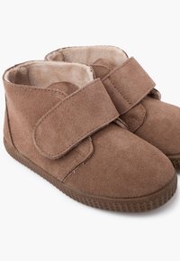 Paio di scarpe per bambini in suede marrone con cinturini a strappo e morbida fodera in peluche, dotate di suole in gomma testurizzata.
