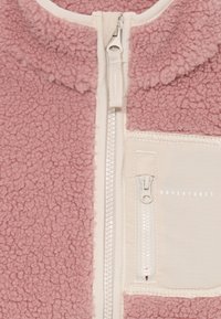 Fleecejacke in zartem Pink mit einem cremefarbenen Reißverschluss und Taschen. Sie hat eine strukturierte Oberfläche, einen Stehkragen und ein gesticktes Detail mit der Aufschrift "ABENTEUER".