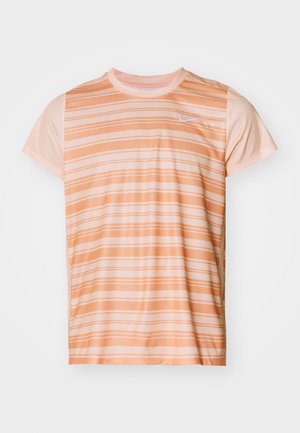 Camiseta de manga corta de Nike hecha de una tela ligera, con rayas horizontales en melocotón y crema, y un pequeño logotipo blanco en el pecho.