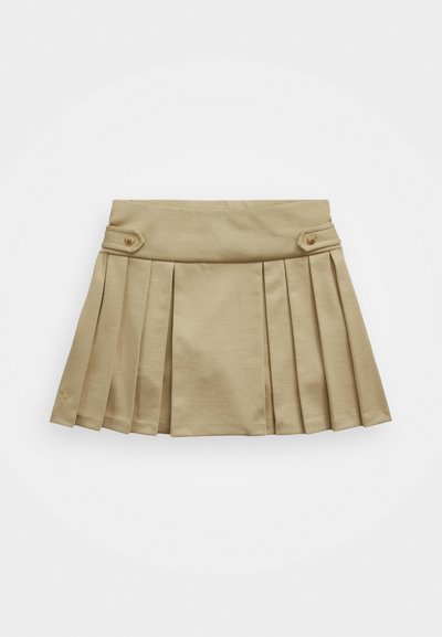 Khaki värvi volditud seelik siledast materjalist, millel on silmatorkavad paelad vöökohas ja kaks eesmist nuppu. Alumises vasakus nurgas on logo.