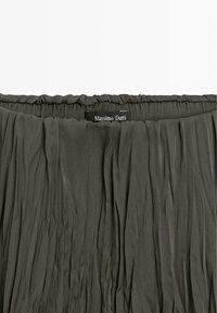 Jupe plissée vert olive foncé avec une taille élastique et une étiquette de marque "Massimo Dutti" cousue au centre du dos.