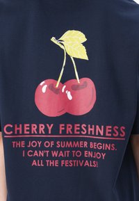 T-shirt blu navy con una grafica di due ciliegie rosse con foglie verdi e la scritta "CILIEGIE FRESCHE" in rosso bold sotto il design.