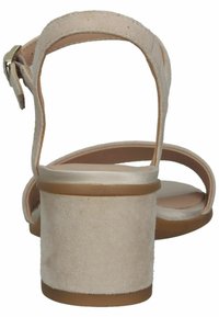 Sandal in suede beige con tacco, con cinturino alla caviglia, aperta sul retro e con tacco cilindrico. Texture morbida e design semplice con una soletta di tonalità chiara.