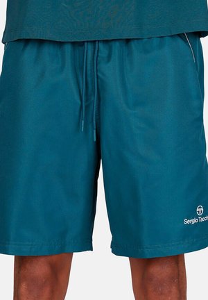 Turkooise short met trekkoord, gedragen met een bijpassend turkoois shirt, waarbij de benen zichtbaar zijn van halverwege de dij tot de knie, met het Sergio Tacchini-logo op de shorts.