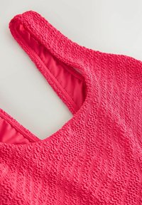 Top de costum de baie din material texturat roz aprins, cu decolteu rotund și căptușeală interioară vizibilă pe fundal neutru.