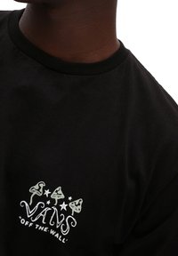 Camiseta de algodón negra con un gráfico de logo en blanco y verde que presenta hongos y estrellas, escote redondo clásico, corte relajado.