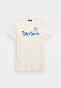 T-shirt en coton crème avec logo bleu "Polo Ralph Lauren" et graphique de soleil. Manches courtes et col rond avec une coupe standard.