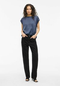 Top corto in satin navy a maniche corte abbinato a jeans neri a vita alta. Un paio di sandali neri con apertura sulla punta completano il look. Design semplice ed elegante.