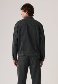 Σκούρο γκρι τζιν μπουφάν με κατακόρυφο ριγέ σχέδιο, κλείσιμο με κουμπιά και πλαϊνές τσέπες. Χαλαρή εφαρμογή με κλασικό γιακά και μακριά μανίκια.