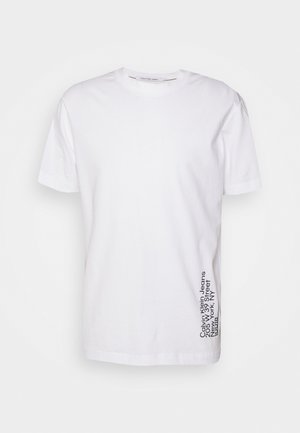 T-shirt bianca in cotone con maniche corte, caratterizzata da una scollatura tonda e dettagli di testo verticale nero sul lato inferiore sinistro.