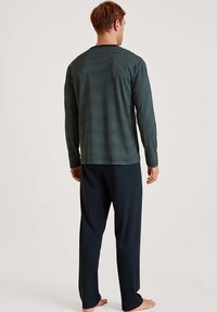 Long-sleeve, navy and teal striped top with crew neckline, paired with solid dark pants; soft material, relaxed fit, minimalistic design.