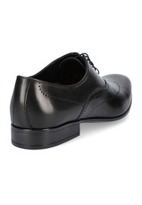 Czarne skórzane buty na płaskim obcasie, z zaokrąglonym noskiem i dekoracyjnymi perforacjami po bokach. Gładka faktura, minimalistyczny design.