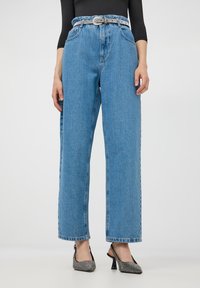 Jasnoniebieskie spodnie z wysokim stanem i szerokimi nogawkami, wykonane z teksturowanej tkaniny, z pięcioma kieszeniami i paskiem z metalową klamrą.