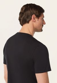 Zwart shirt met korte mouwen en een ronde hals. Gemaakt van gladde stof, het heeft nette naden en een getailleerde pasvorm.