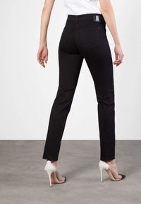 Czarne skinny jeans z wysokim stanem, z tylnymi kieszeniami i gładką teksturą. Połączone z eleganckimi białymi szpilkami.