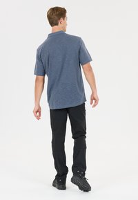 Grå, kortärmad polo med en subtil textur, kombinerad med svarta, åtsittande byxor och mörka skor. Setet är avslappnat och funktionellt.