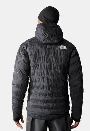 Giacca a puffo nera isolata con cappuccio aderente, cuciture verticali e logo sulla spalla sinistra. Materiale liscio e lucido con polsini elasticizzati.