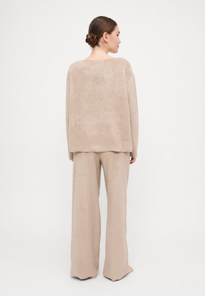 Beige two-piece outfit made of soft fabric. The top has a loose fit with a rectangular shape, and the pants are wide-legged and full-length.