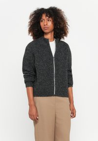 Cardigã de malha cinza escuro com fecho éclair, colarinho alto, punhos e bainha canelados. Fecho éclair cinza claro e tecido texturizado.