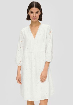 Robe blanche avec un décolleté en V, des manches bouffantes et des détails brodés. Présente des motifs découpés et une coupe décontractée, arrivant au-dessus du genou.