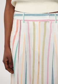 Lahka lanena hlače z navpičnimi črtami v pastelnih barvah, vključno z roza, oranžno, zeleno in modro, z ustreznim pasom.