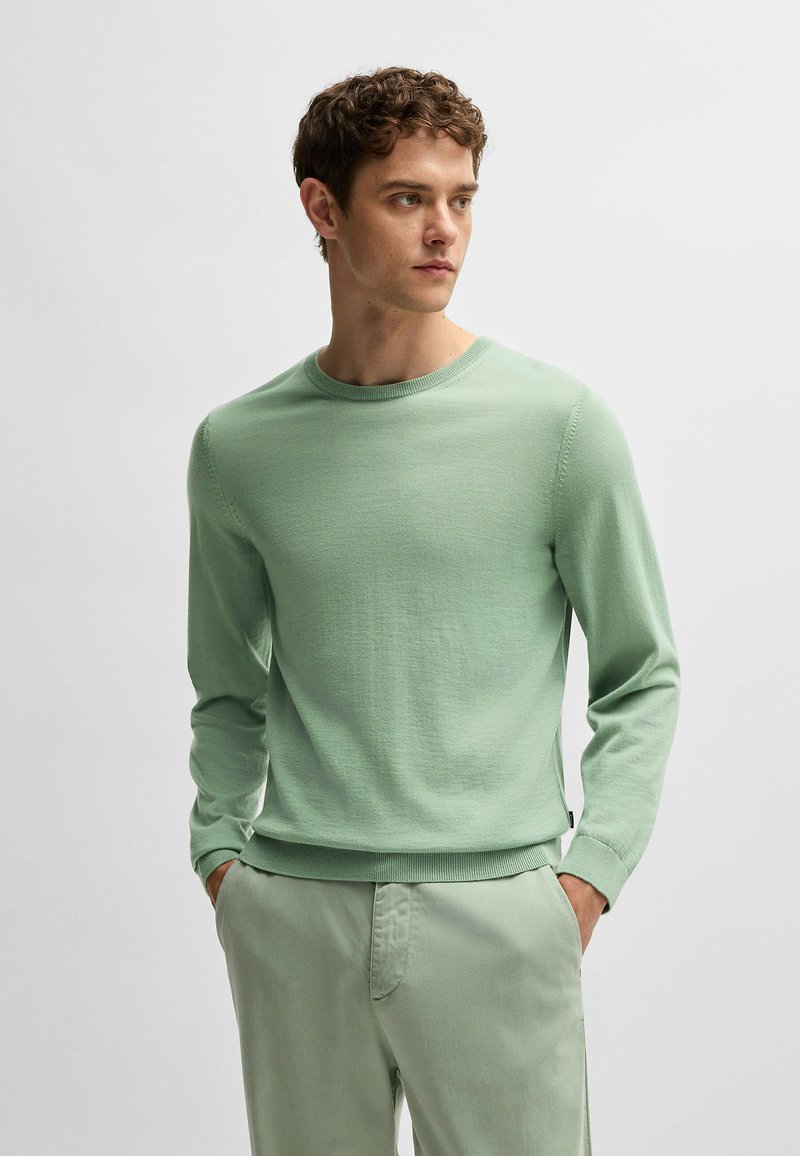Hellgrüner langer Pullover mit Rundhalsausschnitt und gerippten Bündchen. Weiche Textur und minimalistisches Design, kombiniert mit passenden hellgrünen Hosen.
