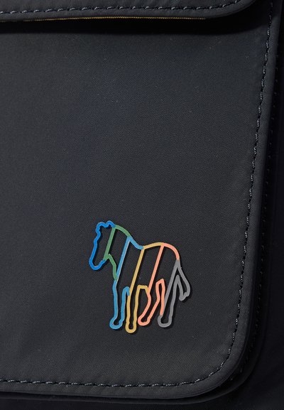 Svart stoffpose med en fargerik stripete zebra-logo på forsiden. Sømmen er i en kontrasterende farge. Generelt glatt tekstur.