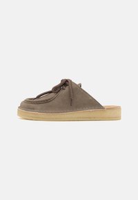 Scarpa slip-on in suede taupe con punta rotonda, caratterizzata da un dettaglio in lacci intrecciati e suola in gomma naturale per una presa ottimale.