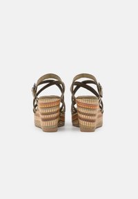 Groene suede wedge sandalen met kruislings gespannen banden, een gestructureerde meerkleurige geweven hak en een verhoogde achterkant voor ondersteuning.