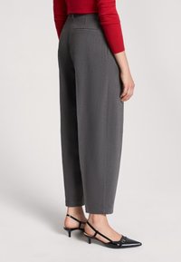 Pantaloni grigi a vita alta con una vestibilità rilassata e una consistenza fine. Abbinati a décolleté slingback nere a punta.