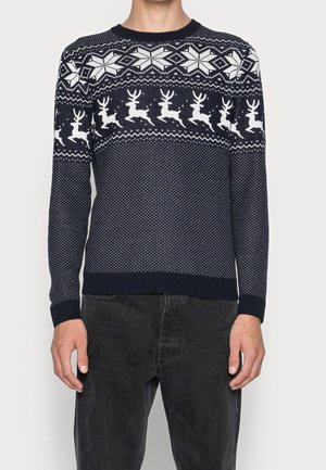 Navy blue sweater featuring a white reindeer pattern, snowflakes, and geometric designs. Made from knit fabric with a ribbed neckline and cuffs.