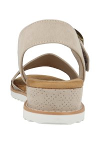 Sandalia beige con un suave upper de ante, plantilla acolchada, suela de goma blanca y detalles perforados en la correa trasera.